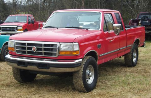 2007 Ford Mustang - A red Ford F-250 pickup truck is parked outdoors with other vehicles in the background.
