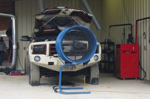 2007 Ford Mustang - A truck is positioned on a dynamometer for testing, with a large fan directed at its front and a red dyno machine nearby.