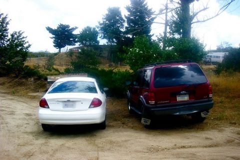 2000 Ford Taurus - A white 2000 Ford Taurus and a red SUV are parked side-by-side in an outdoor lot.