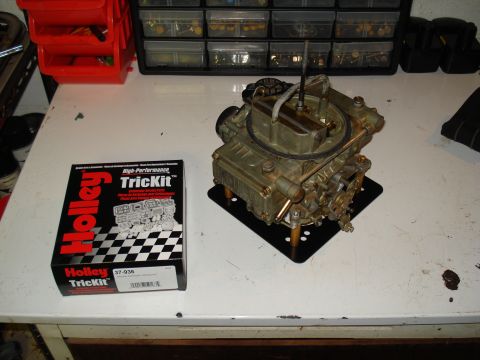 1984 Ford Bronco - A Holley TrickKit carburetor and its packaging are displayed on a workbench, alongside various storage containers.
