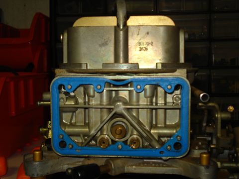 1984 Ford Bronco - A close-up view of a carburetor, showing its internal components and a blue gasket seal.