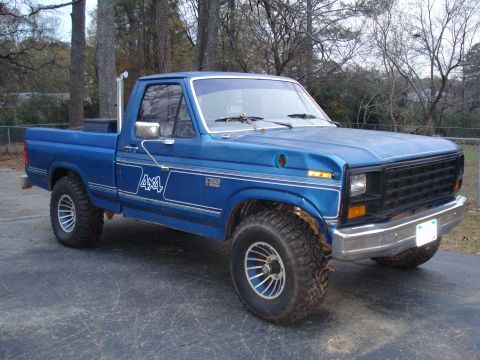 1985 Ford F-150 - This 1985 Ford F-150 pickup truck features a blue paint job and 4x4 badging.