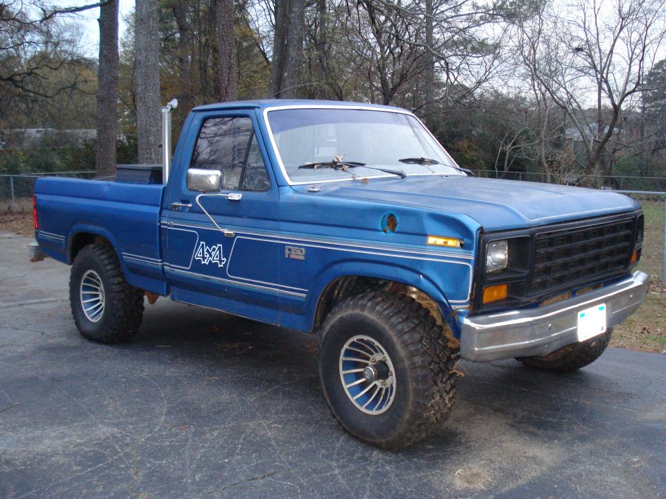 Blue 1985 Ford F-150 pickup truck with 4x4 decals and aftermarket wheels
