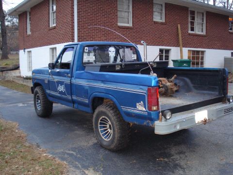 1985 Ford F-150 - A blue pickup truck, likely from the early 1980s, is parked outside a residential building.