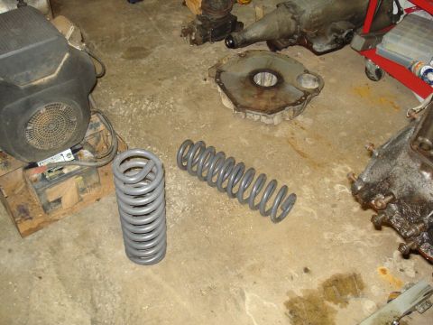 1991 Ford Bronco - Various automotive parts and a lawnmower engine are laid out on a garage floor.