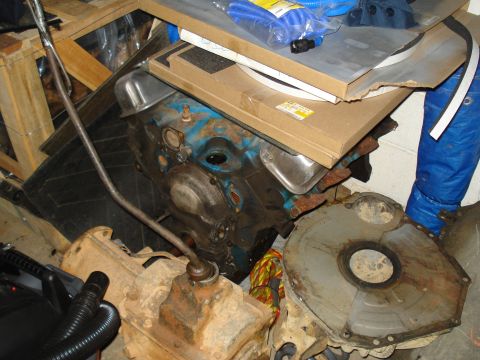 1991 Ford Bronco - Various engine and transmission components are stored together, including a blue engine block and a rusty transmission housing.