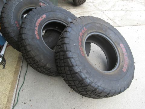 1986 Ford Bronco - A set of General Grabber tires are laid out on a concrete surface, with visible tread patterns.