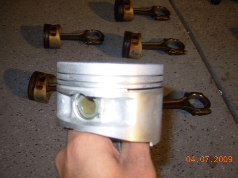1991 Ford Taurus - Several pistons and connecting rods are laid out on a garage floor.