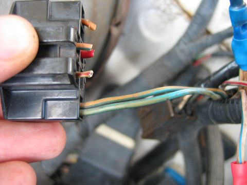 1992 Ford Bronco - Close-up of a hand holding an electrical connector with exposed wires, part of a vehicle's wiring harness.