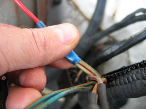 1992 Ford Bronco - Close-up of a hand connecting electrical wires, likely for a vehicle repair or modification.