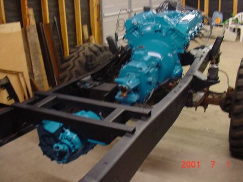 1978 Ford Bronco - The chassis of a vehicle is shown with its engine and transmission assembly, painted a vibrant blue.