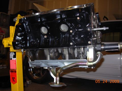 1991 Ford Taurus - A black engine block is mounted on a yellow engine stand, with a portion of a white vehicle visible in the background.