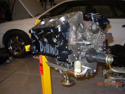 1991 Ford Taurus - Engine block on a stand in front of a white car with its hood up. A date stamp reads 05.24.2009.