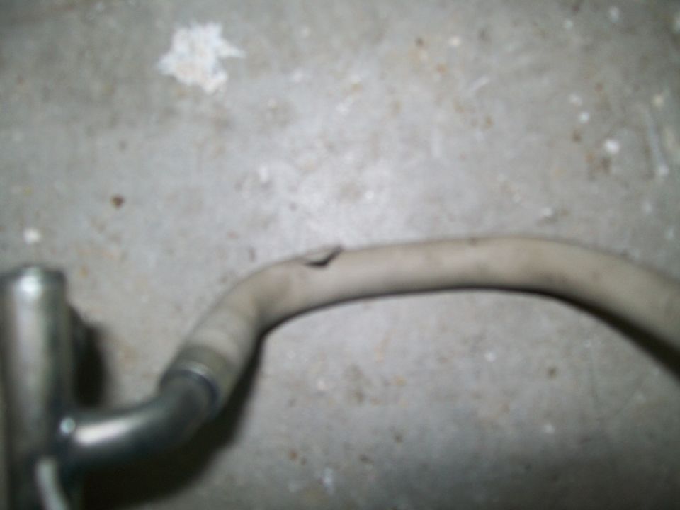 Exhaust pipe with a hole in it, resting on a concrete floor