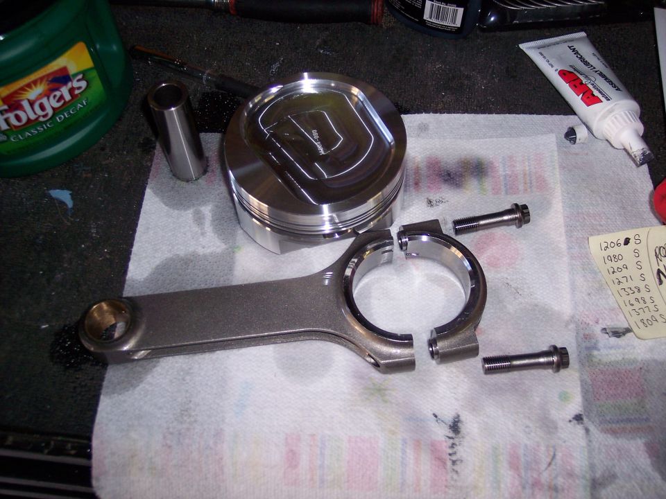 Piston and connecting rod assembly with bolts on a paper towel. A tube of assembly lubricant is nearby