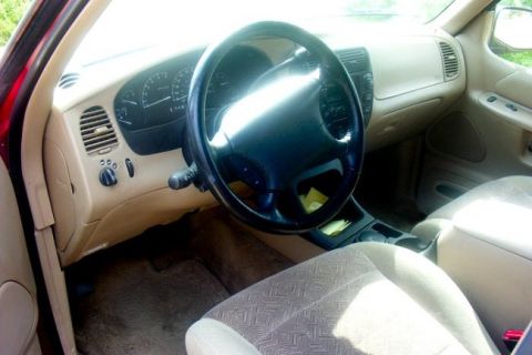 2000 Ford Taurus - The interior of a car shows tan upholstery and a black steering wheel, with a watermark at the bottom right.