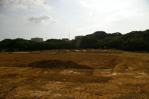 1986 Ford Bronco - A wide view of a cleared and graded area, possibly for construction, with distant structures and trees under a cloudy sky.