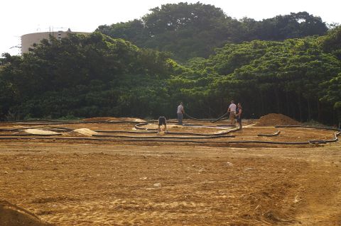 1986 Ford Bronco - Workers construct an RC track with tubing and dirt mounds under a treeline.