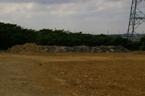1986 Ford Bronco - A wide view of a construction site piles of debris and a prominent power line tower under an overcast sky.