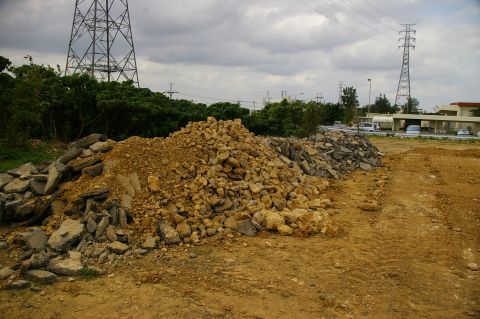 1986 Ford Bronco - A construction site with piles of debris and a large power line tower under a cloudy sky.