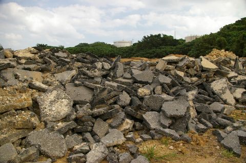 1986 Ford Bronco - A large pile of broken asphalt and concrete rubble sits in a field under a cloudy sky.