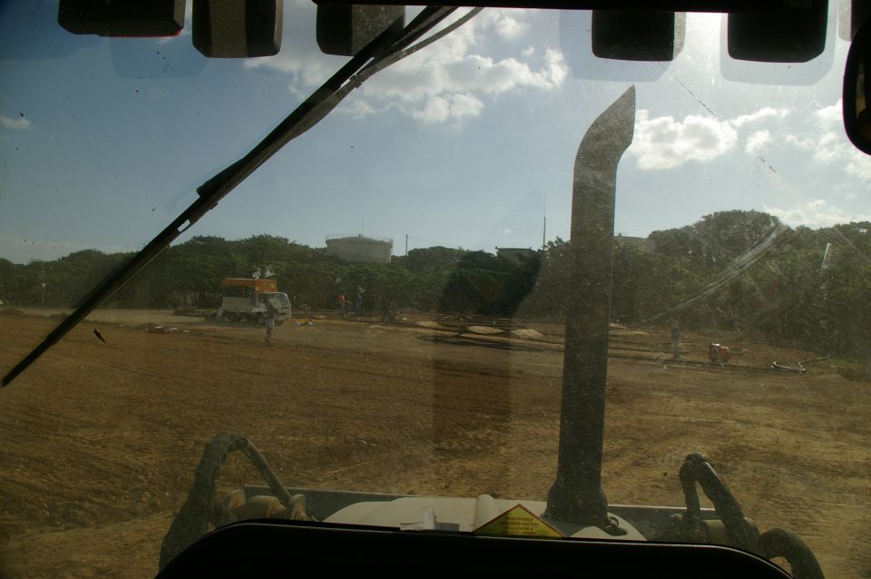 View from inside a vehicle looking out at a construction site with a truck and excavator
