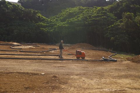 1986 Ford Bronco - A person is compacting the dirt for a track with a small roller.