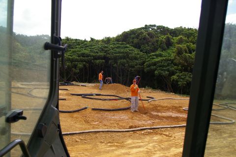1986 Ford Bronco - Workers are on a dirt construction site with hoses laid out on the ground, viewed from inside a vehicle.