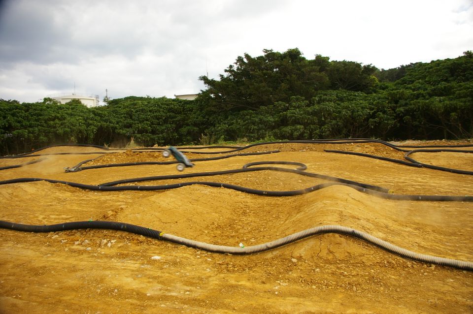 Remote control car mid-air over a dirt track with black tubing borders