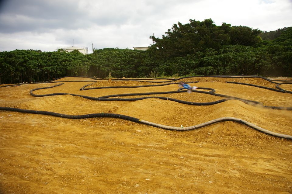 Radio-controlled car racing on a dirt track with black tubing borders