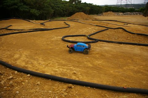 1986 Ford Bronco - A remote controlled car navigates a dirt track marked with black tubing.