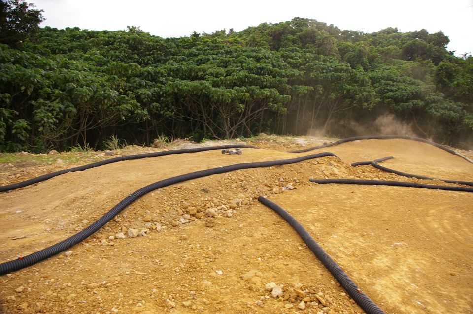 Remote control car on a dusty dirt track with trees in the background