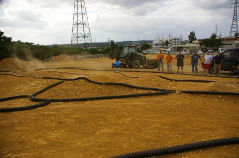 1986 Ford Bronco - People observe an RC car track with construction equipment in the background under a cloudy sky.