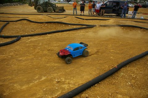 1986 Ford Bronco - RC car racing on a dirt track with spectators in the background.