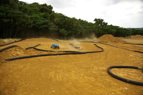 1986 Ford Bronco - RC cars kick up dust as they navigate a winding dirt track.