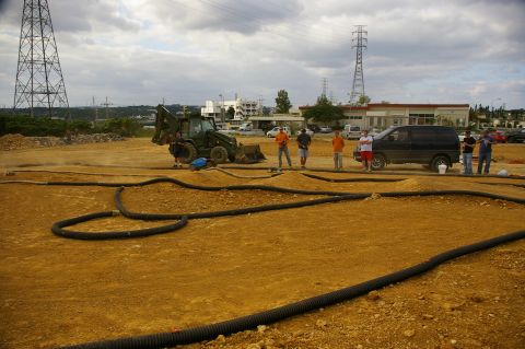 1986 Ford Bronco - A group of people stand around an RC track, with a backhoe and a black van parked nearby.