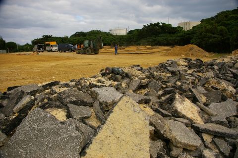 1986 Ford Bronco - A construction site is shown with various vehicles and a large pile of broken asphalt in the foreground.