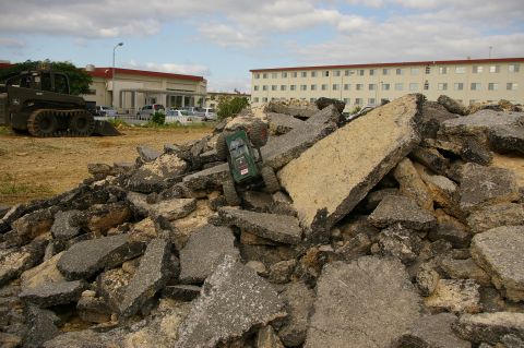 1986 Ford Bronco - A remote control car is positioned on a mound of rubble, with buildings visible in the distance under a cloudy sky.