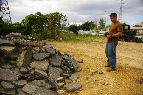 1986 Ford Bronco - A person operates a remote control car near a construction debris pile with a tracked vehicle in the distance.