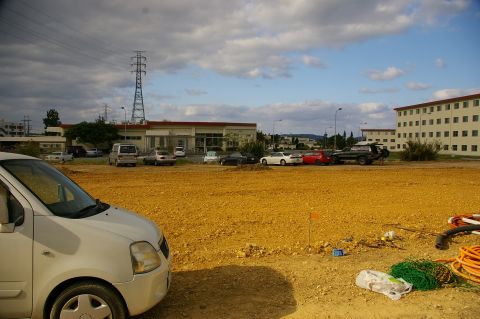 1986 Ford Bronco - A wide view of a parking lot filled with vehicles, adjacent to buildings and a power line tower.