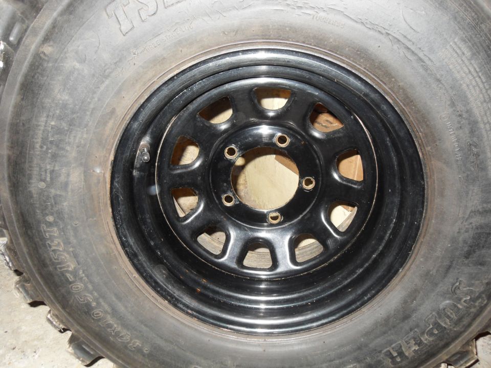 Close-up of a tire with 33x12.50-15LT markings and a black steel wheel with 5 lug holes