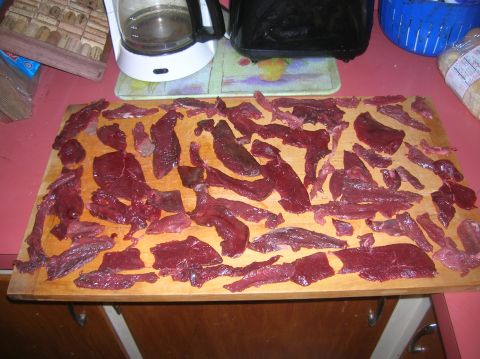 1996 Ford Bronco - Slices of raw meat are laid out on a wooden cutting board, possibly for drying or preparation.