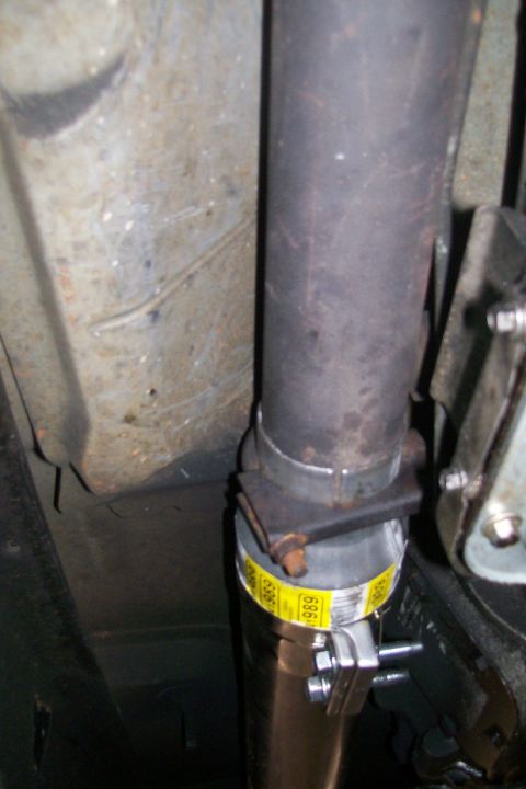 1992 Ford C-350 (Centurion Conversions) - Close-up of an exhaust pipe with a clamp that has visible text.