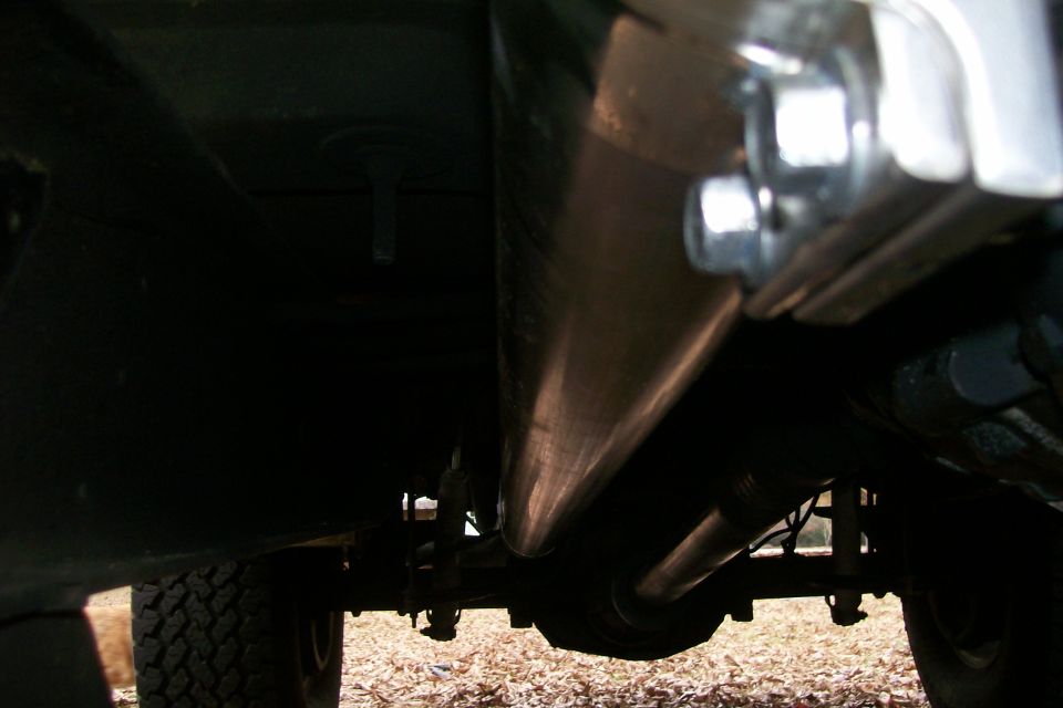 Close-up of exhaust pipes and suspension components under a vehicle