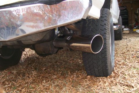 1992 Ford C-350 (Centurion Conversions) - A shiny new exhaust pipe is installed on the rear of a truck, with a second vehicle in the background.