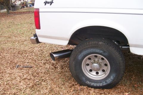 1992 Ford C-350 (Centurion Conversions) - The rear of a white pickup truck is shown, with a visible chrome exhaust pipe and a '4x4' decal on the bed.