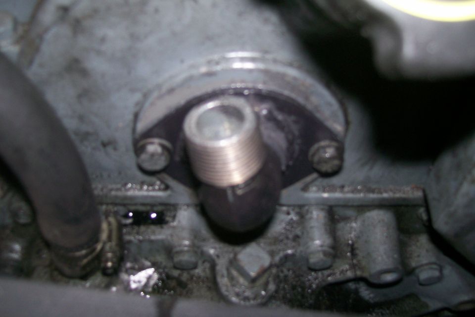 Engine block with a threaded fitting and gasket, near a hose