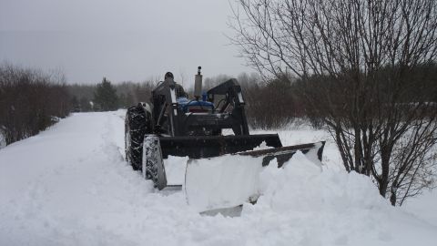 2000 Chevrolet Tahoe - A tractor is clearing snow from a path on a cloudy winter day.