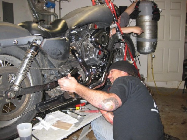 Mechanic working on a motorcycle engine, which is suspended by red straps