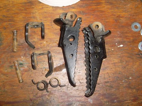 1987 Honda 250 R - Motorcycle foot pegs and associated hardware are displayed on a wooden workbench.
